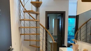 Une cuisine moderne avec des armoires blanches, un plan de travail en bois et un escalier en colimaçon avec des marches en bois.