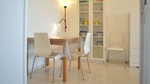 A dining area with a table, chairs, a lamp, and a cabinet with dishes. - Family apartment sleeps 6 Banyuls-sur-Mer A/C, private parking, near beaches (Banyuls-sur-Mer)