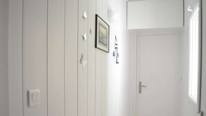 A hallway with white walls, a framed picture, and a door with a window. - Family apartment sleeps 6 Banyuls-sur-Mer A/C, private parking, near beaches (Banyuls-sur-Mer)