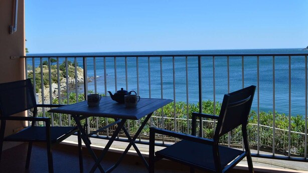 A balcony with a table and chairs, overlooking a coastal view. - Family apartment sleeps 6 Banyuls-sur-Mer A/C, private parking, near beaches (Banyuls-sur-Mer)