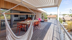 Une terrasse en bois avec un hamac, une table à manger et des chaises.