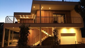 Une maison moderne à deux étages, dotée d’un balcon, d’un escalier et d’un garage.