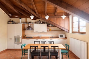 A kitchen with a wooden ceiling, white cabinets, a dining table with chairs, and a window. - Villa Rosa - villa surrounded by greenery with private garden, ideal for families (Pian Nava)