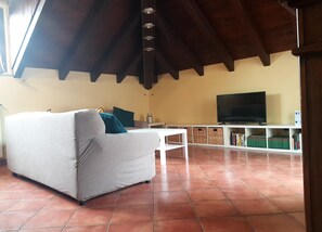 A living room with a sofa, a television, and a bookshelf. - Villa Rosa - villa surrounded by greenery with private garden, ideal for families (Pian Nava)