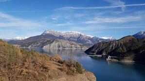 Eine Berglandschaft mit einem See, einer Brücke und einem kleinen Gebäude.