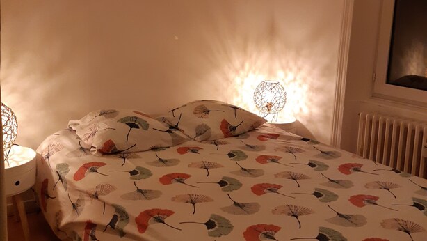 Ein Schlafzimmer mit Bett, Nachttisch, Lampe und Heizkörper.