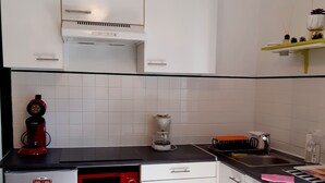 Eine kleine Küche mit weißen Schränken, einer Mikrowelle, einer Kaffeemaschine und einem kleinen Kühlschrank.