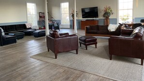 Un salon spacieux doté d’un grand téléviseur, de nombreux sièges et d’un plancher en bois.
