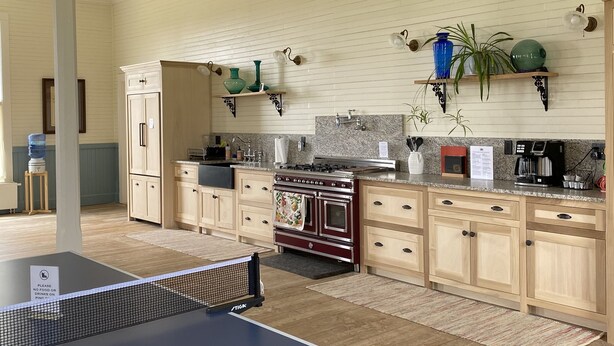 Une cuisine spacieuse équipée d’une table de ping-pong, de meubles en bois, d’une cuisinière et agrémentée de plantes décoratives.