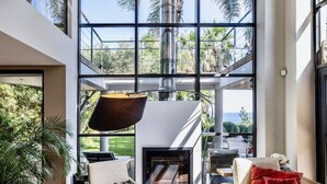 Un salon moderne doté d’une cheminée, de grandes fenêtres et offrant une vue sur l’extérieur.