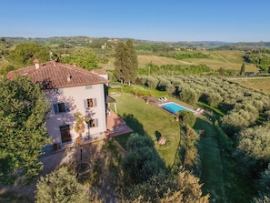 Une villa avec piscine, entourée d’une végétation luxuriante et de vignobles.