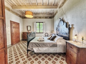 Een slaapkamer met een bed, een houten garderobe en een raam met luiken.