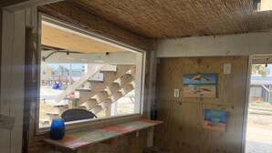Een kleine houten kamer met een raam, een krukje en een plank waarop een blauw voorwerp staat.