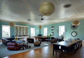 A spacious living room with a high ceiling, a large wooden dining table, and comfortable seating. - Luxury Apartment overlooking Center Harbor in Brooklin (Brooklin)