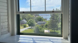 A window with a view of a residential area, including houses and trees. - Luxury Apartment overlooking Center Harbor in Brooklin (Brooklin)