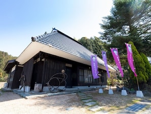 Traditional Japanese building with a sculpture in the foreground, set amidst a serene natural setting.