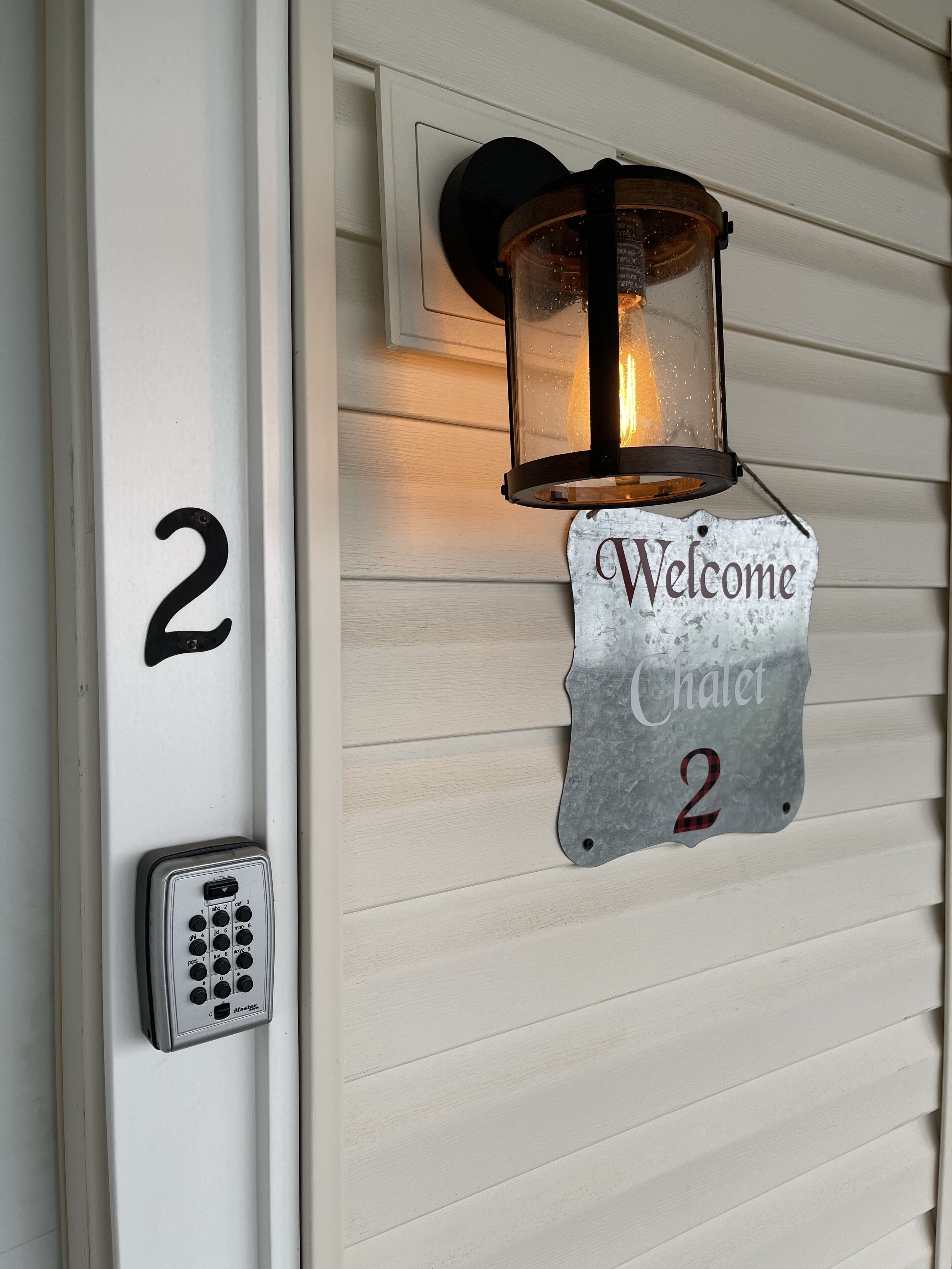 A house number '2', a 'Welcome Chalet 2' sign, and a keypad door lock.