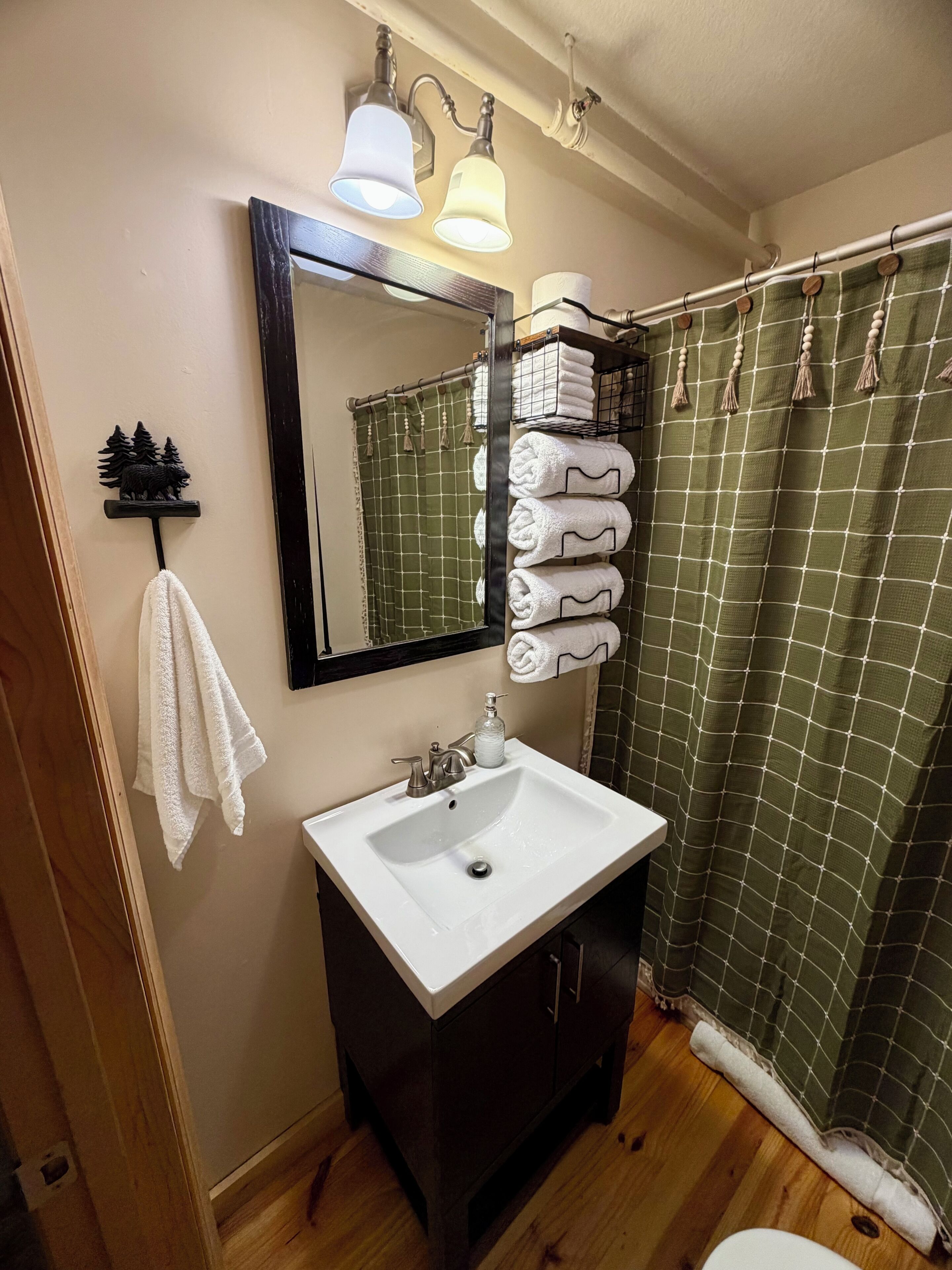 Une salle de bain équipée d’un lavabo, d’un miroir, d’un porte-serviettes et d’un rideau de douche.