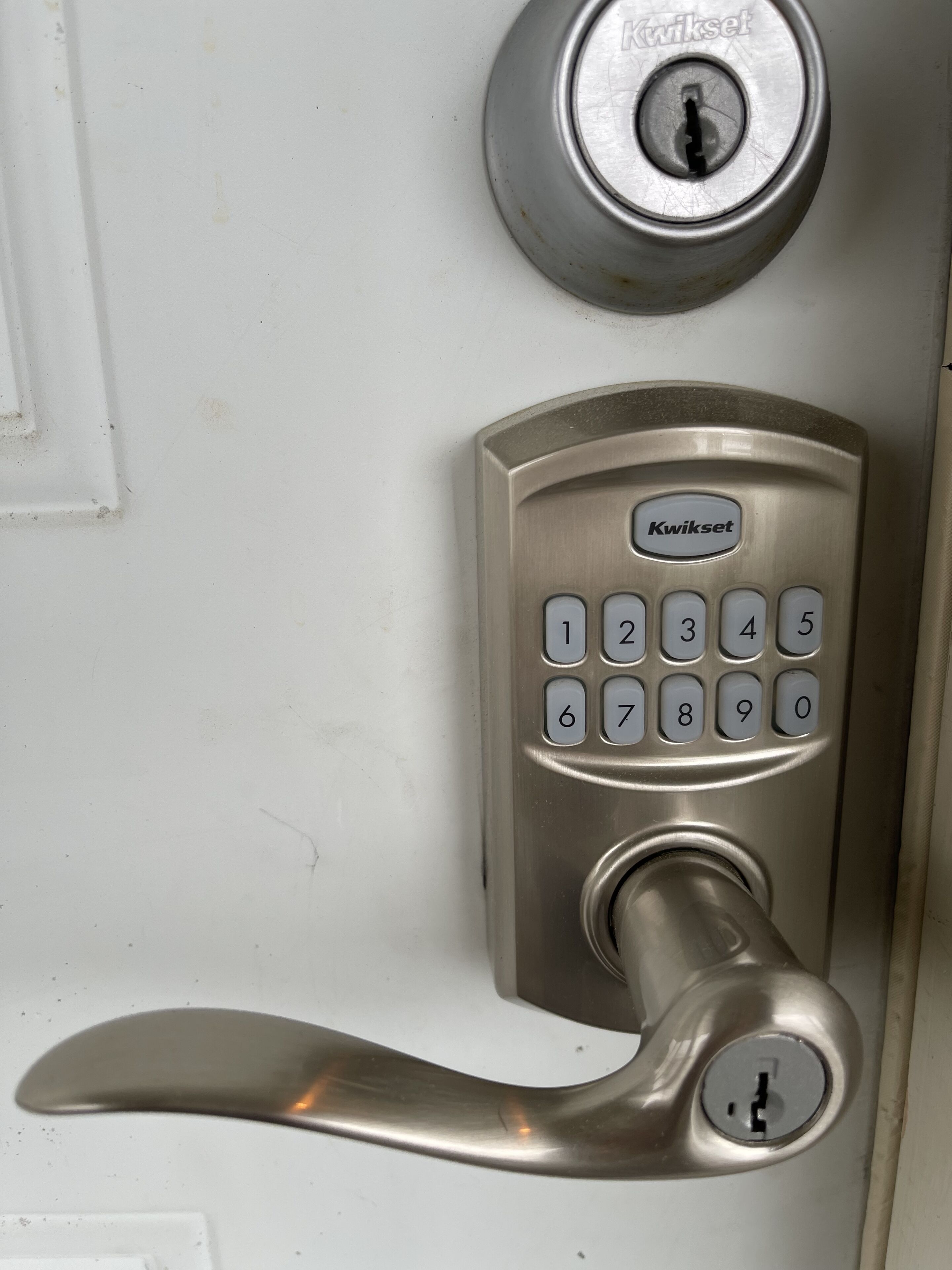 A Kwikset door lock with a numeric keypad and a lever handle.