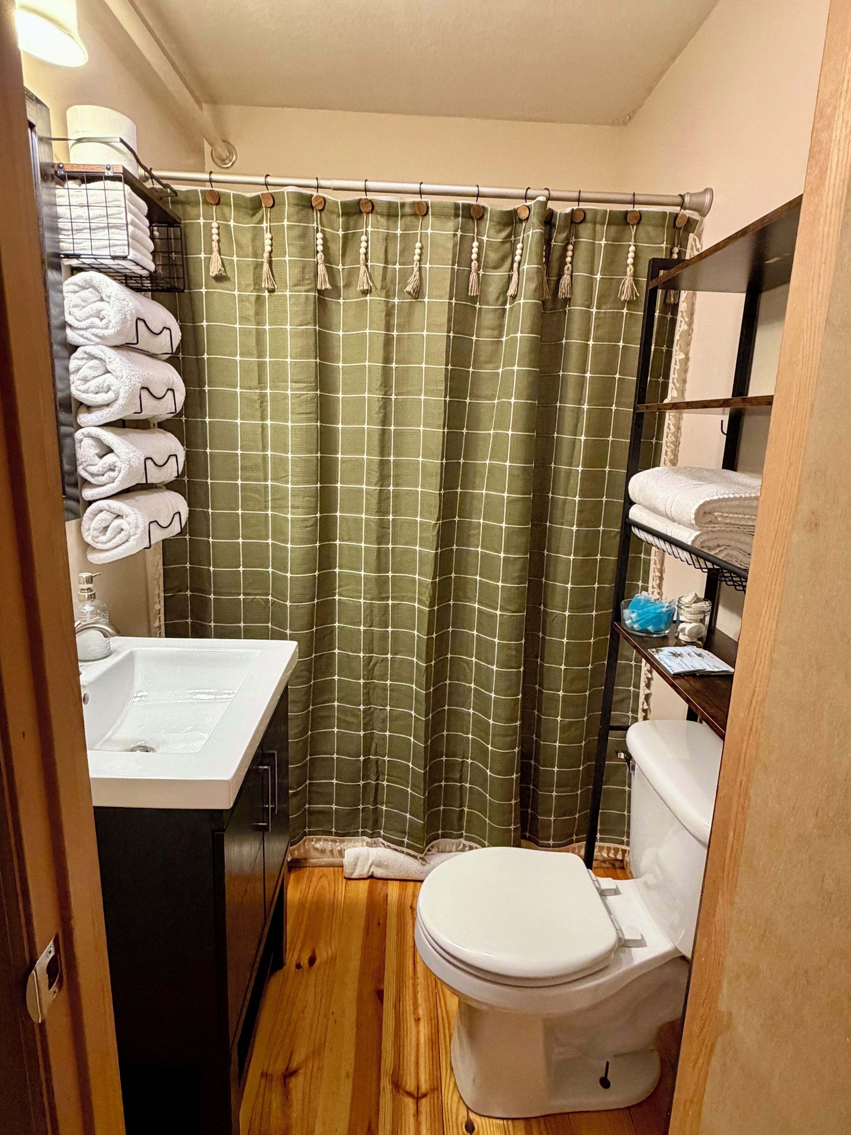 A compact bathroom with a white sink, toilet, and a shower curtain with a grid pattern.