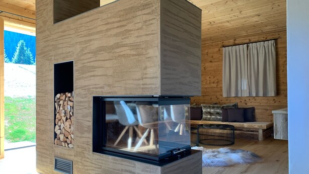 A modern living room with a built-in fireplace, wooden flooring, a sofa, and a view of the outdoors.