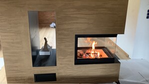 A modern fireplace with a glass front, a small statue on the left, and a visible fire burning inside.