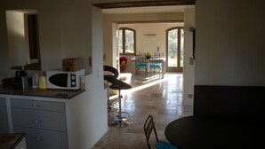 Una cocina con comedor, microondas y una silla.
