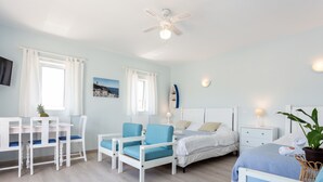 A room with a bed, a desk with chairs, a ceiling fan, and a wall-mounted shelf with a decorative item. - Mariners (1) - Bright and stylish apartment - walk to the beach (Luz)