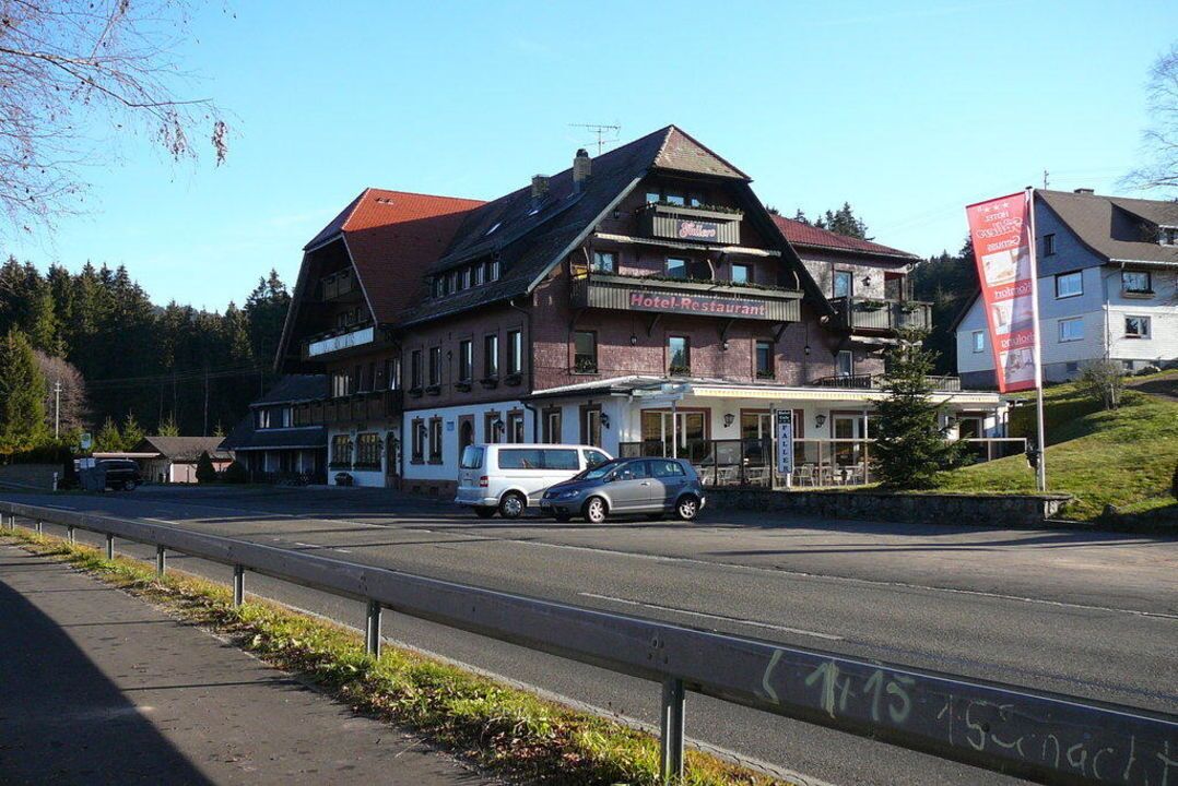 A hotel with a traditional architectural style, featuring a prominent balcony and a sign indicating it is a hotel and restaurant.