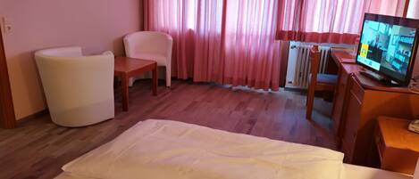 A hotel room with a bed, a desk, a chair, and a television.