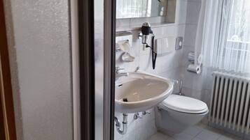 Une salle de bain avec un lavabo blanc, des toilettes et un radiateur.