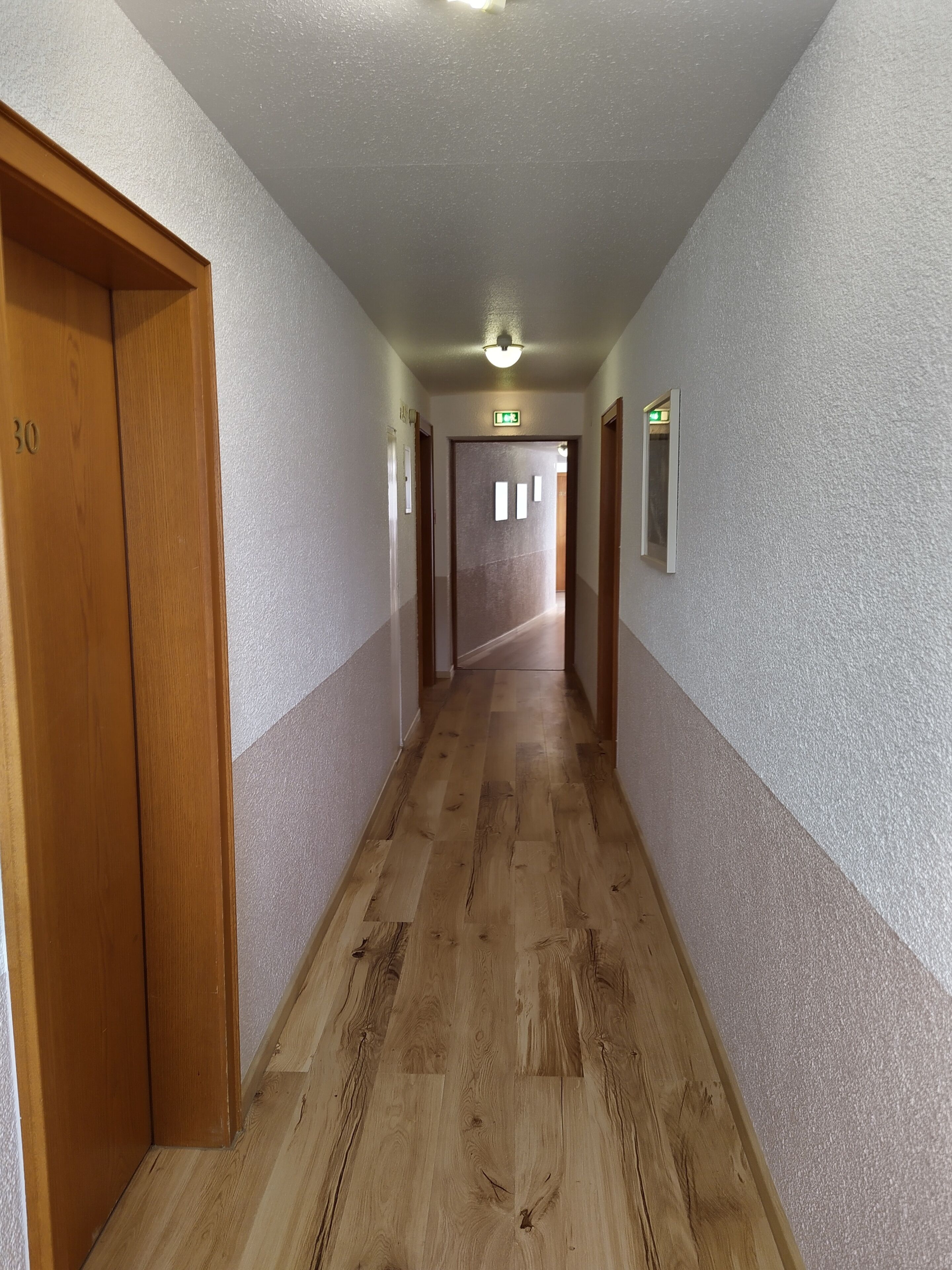 A hallway with wooden doors, a textured wall, and a ceiling light.