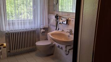 A bathroom with a toilet, sink, and radiator.