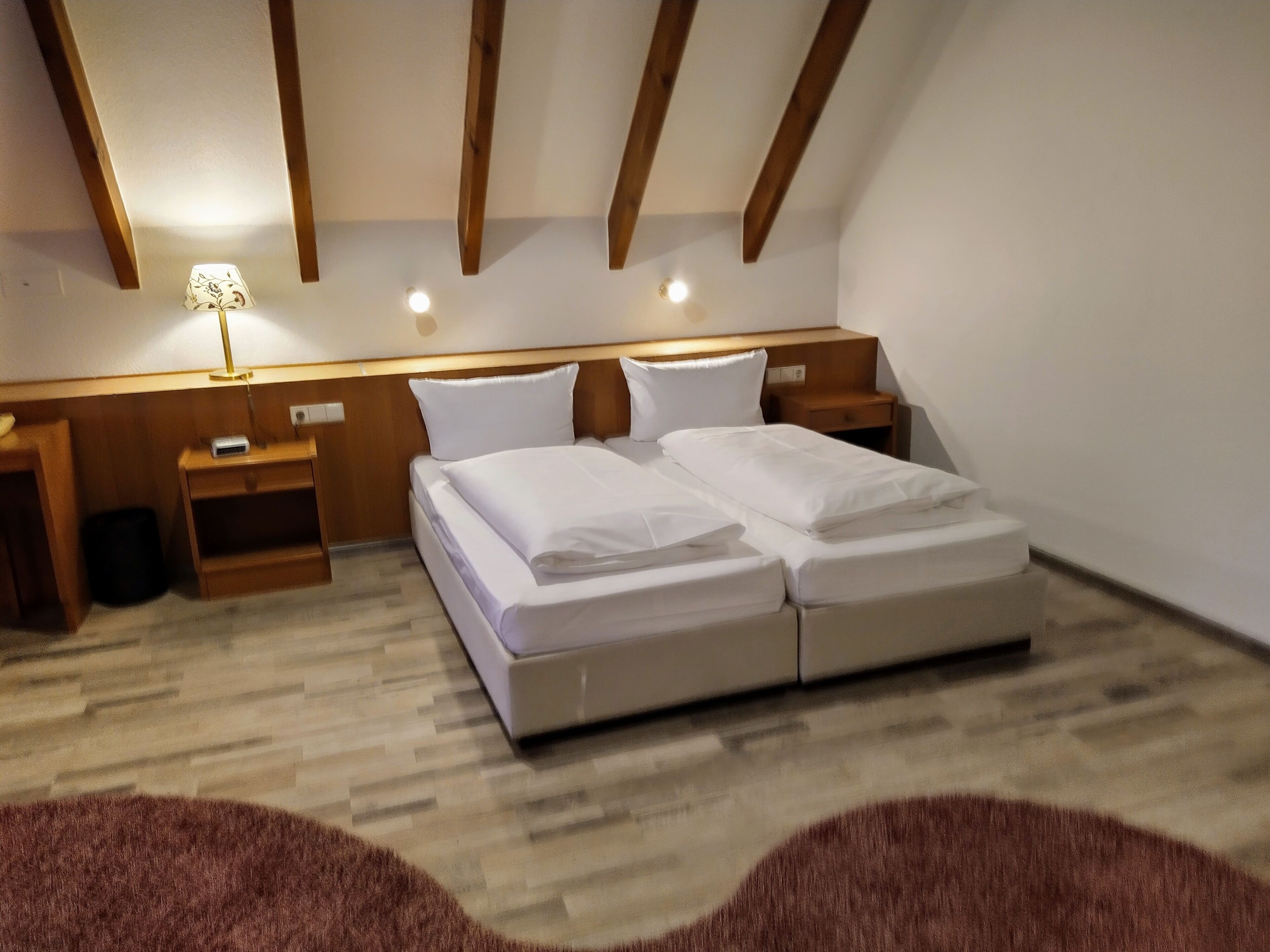A bedroom with a double bed, wooden headboard, bedside tables, and a lamp.
