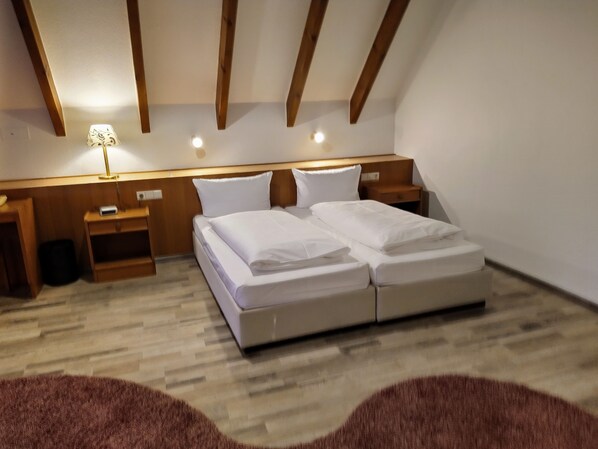 A bedroom with a double bed, wooden headboard, bedside tables, and a lamp.