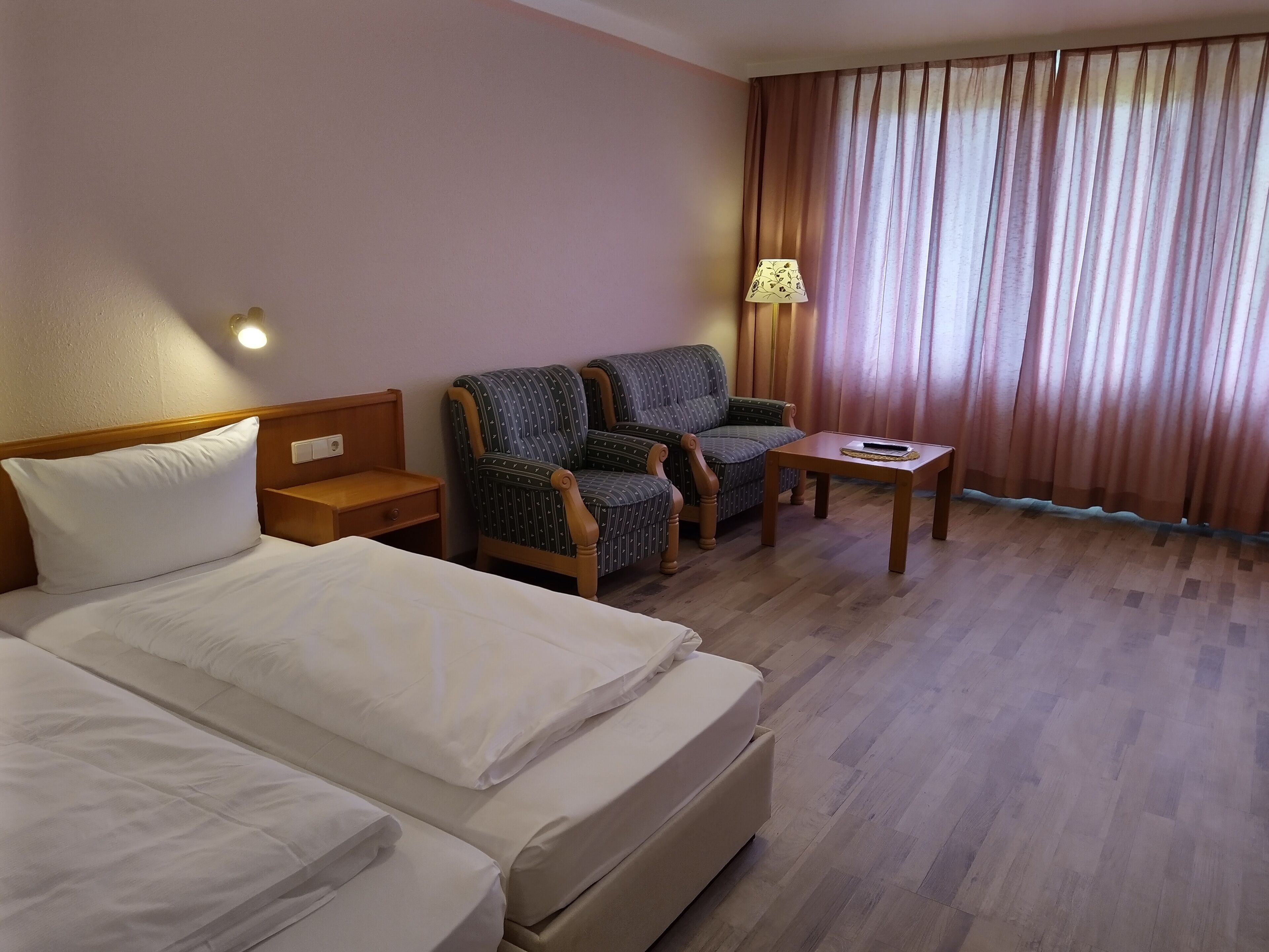 Ein Hotelzimmer mit zwei Betten, einem Schlafsofa, einem kleinen Tisch und einer Lampe.