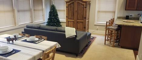 Een eetgedeelte met een gedekte tafel voor twee personen, een bank en een kerstboom.