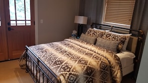Une chambre à coucher avec un lit, une table de chevet, une lampe et une fenêtre avec des stores.