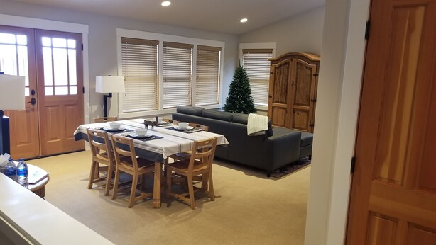 Un coin repas avec une table dressée pour quatre personnes, un canapé, un sapin de Noël et un meuble en bois.