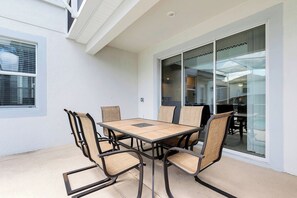 A patio with a table and chairs, a sliding glass door, and a window.