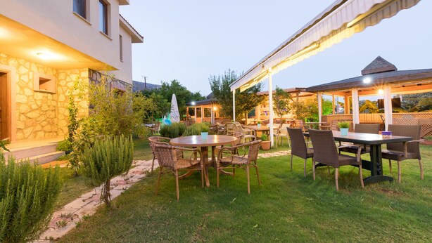 Un patio con una mesa redonda y sillas, rodeado de muros de piedra y follaje.