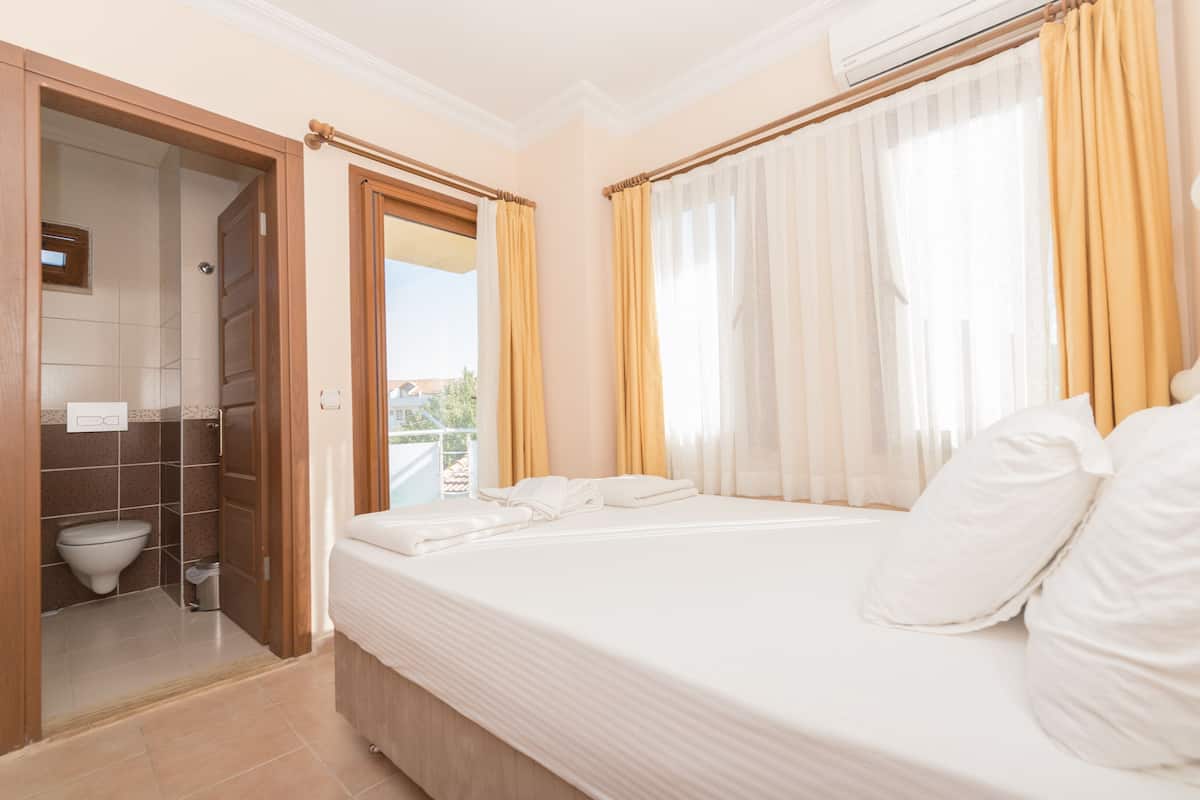 A hotel room with a bed, a bathroom, and a view of the outdoors.
