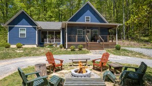 Une cabane dotée d’une véranda, d’un espace salon extérieur et d’un foyer.