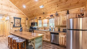 Une cuisine de style rustique, avec des éléments en bois, un îlot central, des tabourets de bar, des appareils en acier inoxydable et des armoires en bois.
