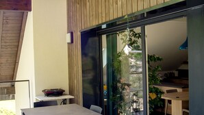Un interior moderno con techo de madera, un comedor con mesa y sillas, y un puerta corrediza de vidrio que da a un espacio exterior con plantas.