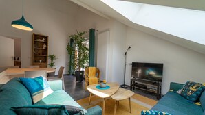 Una sala de estar moderna con techo alto, comedor y televisor.