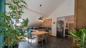 Una cocina moderna con una isla central, suelo de baldosas oscuras y una lámpara colgante.