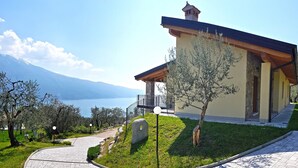 A modern building with a stone facade, a balcony, and a view of a lake and mountains. - Villa Vagne Sunset Lake View Patio (Tremosine)
