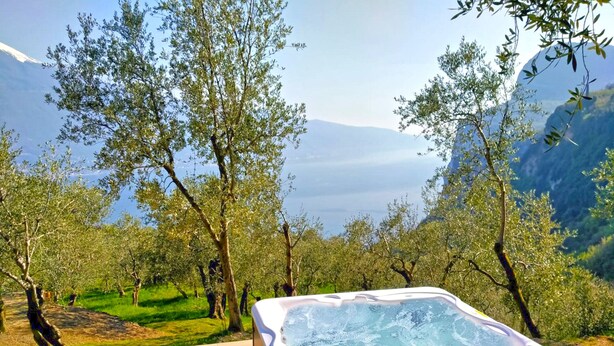 A hot tub on a wooden deck with a mountainous landscape in the background. - Villa Vagne Sunset Lake View Patio (Tremosine)