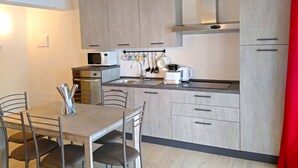 A modern kitchen with light wood cabinets, a microwave, a coffee maker, and a dining table with chairs. - Villa Vagne Sunset Lake View Patio (Tremosine)